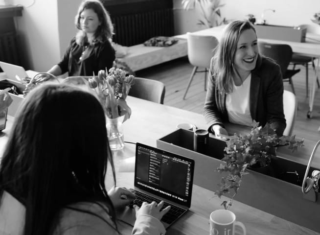 group of 3 people with two on computers and one smiling